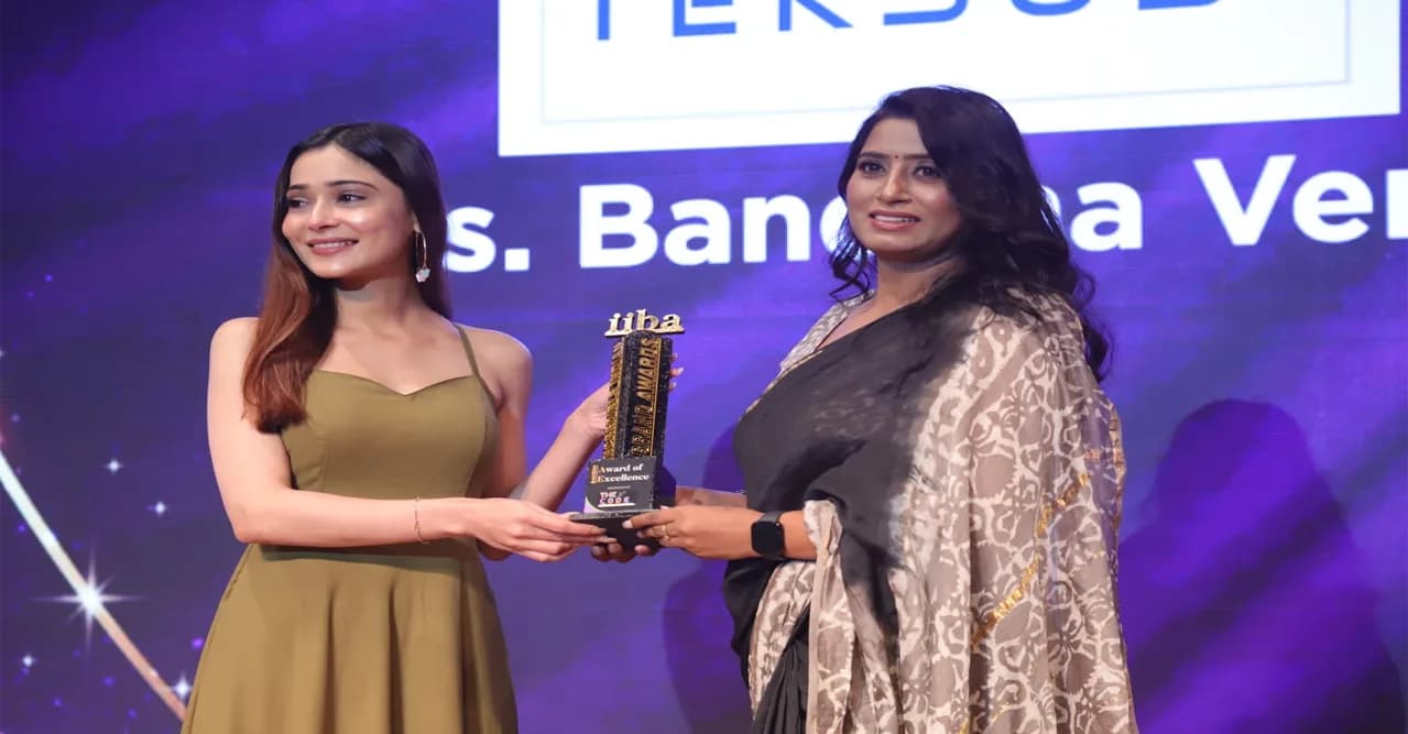 Mrs. Bandana Verma of Teksus Power Solutions accepting the iiba Award of Excellence trophy on stage