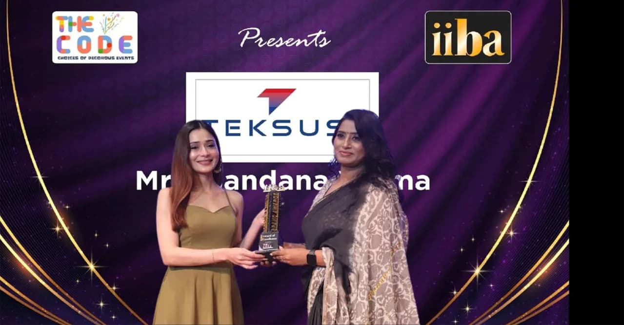 The Teksus award being presented beneath a screen showing the Teksus logo and the name Mrs. Bandana Verma